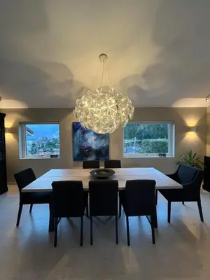 a dining room with a table and chairs and a chandelier at Modern detached house by the mountains & sea in Eidsvåg