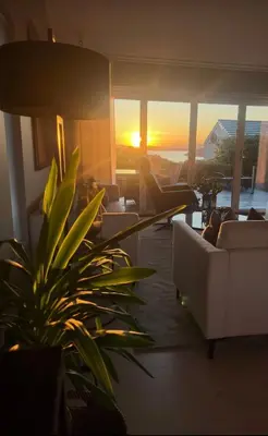 a living room with couches and a sunset at Modern detached house by the mountains & sea in Eidsvåg