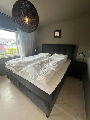 a bedroom with a bed with white sheets and a window at Modern detached house by the mountains & sea in Eidsvåg