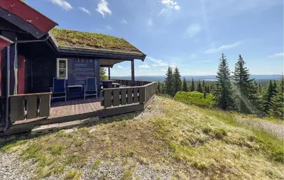 a house with a deck with chairs on a hill at Gorgeous Home In Sjusjøen With Sauna in Sjusjøen