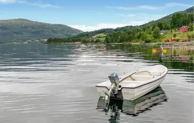 a boat sitting in the water on a lake at 1 Bedroom Amazing Home In Tingvoll in Tingvoll