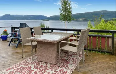 a table and chairs on a deck with a view of the water at 1 Bedroom Amazing Home In Tingvoll in Tingvoll