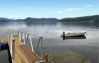 a boat sitting on the water next to a dock at 1 Bedroom Amazing Home In Tingvoll in Tingvoll