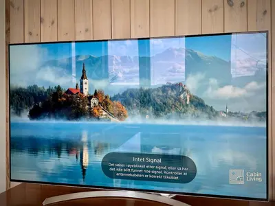 a television screen with a picture of a church and a lake at Ski-In Out apt Hafjell - Sauna and Stunning Views in Hafjell