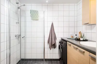 a white tiled bathroom with a shower and a sink at Cozy apartment Trondheim, free parking in the basement in Trondheim