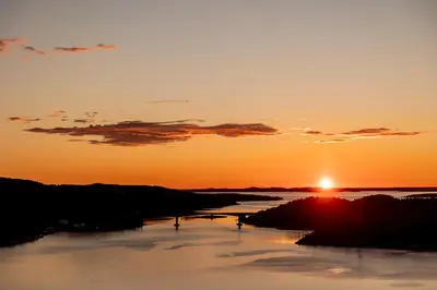 a sunset over a river with the sun setting at Speilhus med badestamp - en unik naturopplevelse in Solem