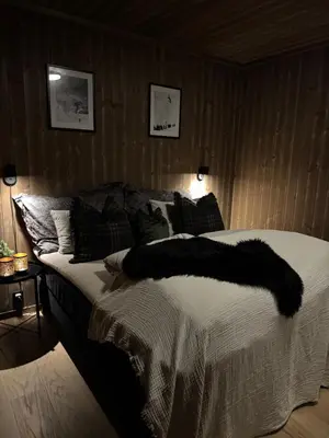 a bedroom with a bed with a black blanket on it at Moderne leilighet ski inn og ski ut med magisk natur in Lii
