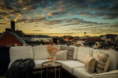 a couch on a balcony with a view of a city at Penthouse apartment in the heart of Bergen with beautiful private rooftop in Bergen