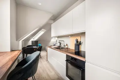 a kitchen with white cabinets and black appliances at Central & Modern Apartment in the Coziest Street in Bergen in Bergen