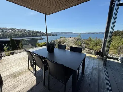a table and chairs on a deck with a view of the water at Villa Vaaganeset in Lii