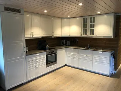 a kitchen with white cabinets and a wooden floor at Familiehytte på Kvamskogen in Kvam