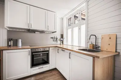 a white kitchen with white cabinets and a sink at Bergen pearl in historic street & easy check-in in Bergen