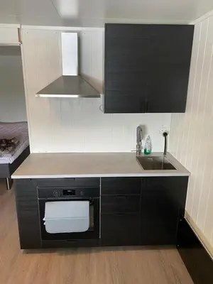 a kitchen with black cabinets and a sink and a counter at Nice little studio centrally located in Lii