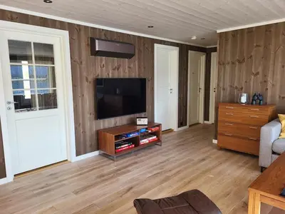 a living room with a flat screen tv on a wooden wall at Hytte ved sjøen in Røyra
