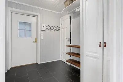 a hallway with a white door and a black tile floor at Trysilfjell 720 by Vacation Trysil in Trysil