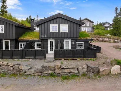 a black house with a stone wall at Cozy Skilodge ski in & out in Trysil in Trysil