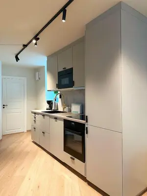 a kitchen with white cabinets and a large refrigerator at Aurum Bergen Apartment in Bergen