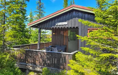 a cabin with a wrap around deck in the woods at 2 Bedroom Nice Home In Hafjell in Hafjell