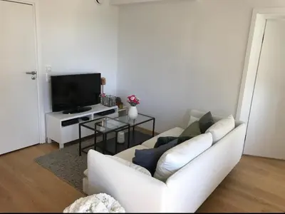 a living room with a white couch and a tv at Lys leilighet på Kaldnes in Lii