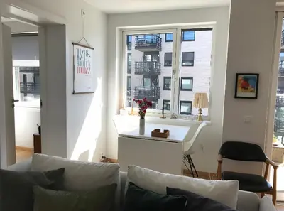 a living room with a couch and a table and windows at Lys leilighet på Kaldnes in Lii