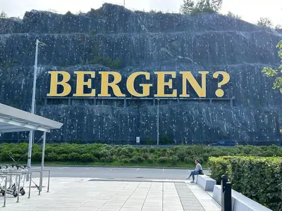 a person sitting on a bench in front of a sign at Family-friendly townhouse on Landås in Lii