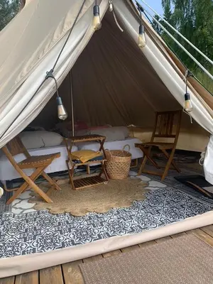 a tent with chairs and a bed in it at Glampingtelt i fjordkanten, Rønlund Hyttepark in Ron