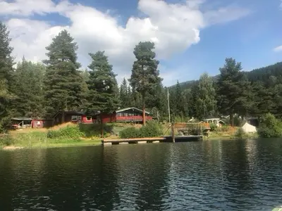 a view of a lake with a dock and houses at Glampingtelt i fjordkanten, Rønlund Hyttepark in Ron