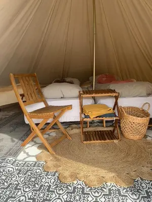 a room with a tent with a chair and a bed at Glampingtelt i fjordkanten, Rønlund Hyttepark in Ron