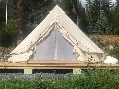 a white tent sitting on top of a wooden platform at Glampingtelt i fjordkanten, Rønlund Hyttepark in Ron
