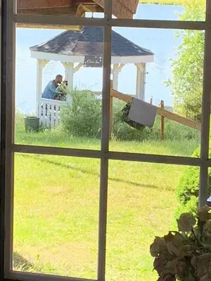 a window view of a man sitting in a gazebo at Glampingtelt i fjordkanten, Rønlund Hyttepark in Ron