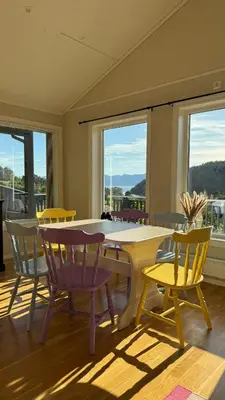 a room with a table and chairs and windows at Cabin by the lake with 3 bedrooms in Kvam