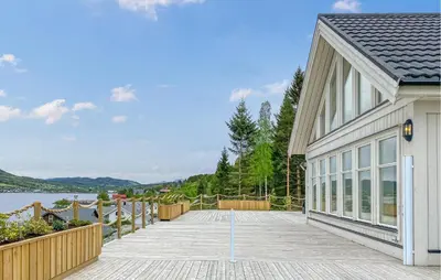 a house with a wooden deck next to a body of water at Pet Friendly Home In Eidsvåg I Romsdal in Eidsvåg