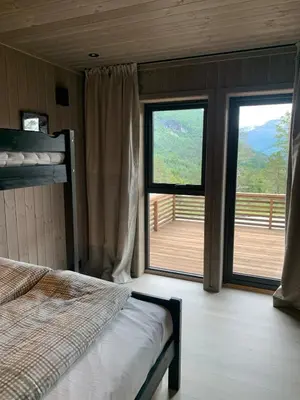 a bedroom with a bed and two windows with a deck at Moderne og romslig familiehytte i Stryn in Stryn