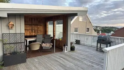 a covered deck with a grill and a desk on a house at KSU Topleiligheten in Kristiansund