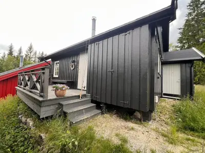 a black house with a porch and stairs to it at Hytte på Norefjell in Surteberg