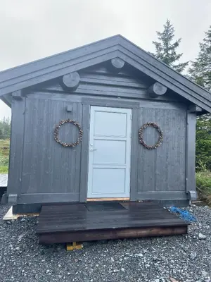 a gray out house with a door and two wreaths at MYLLA - New cabin - Sauna - Hike - Bike - Canoe- Fishing in Jevnaker