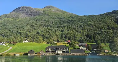 a house on the shore of a lake in front of a mountain at Lakeside apartment in Stryn