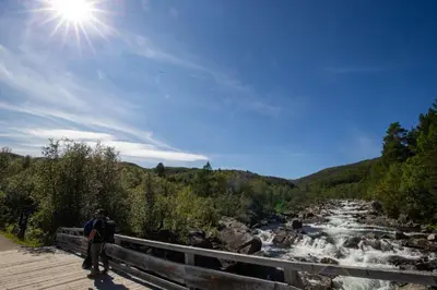 a man walking on a bridge over a river at Stay in central Geilo, 3 bedrooms, linen and towels included in Geilo