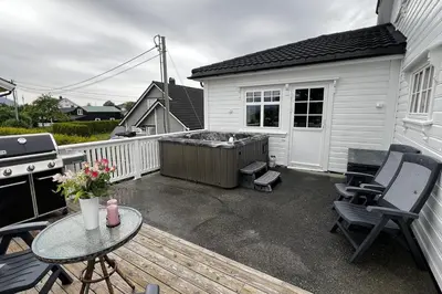 a patio with a hot tub and a table and chairs at Nordic Villa Retreat in Ålesund