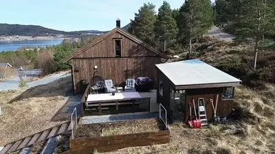 a small cabin with a porch and aestead at Cabin at the end of Skardsøya towards the sea - boat in Bukta