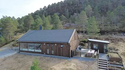 a large wooden cabin in the middle of a field at Cabin at the end of Skardsøya towards the sea - boat in Bukta
