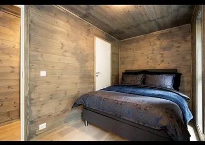a bedroom with a bed in a wooden wall at Cabin at the end of Skardsøya towards the sea - boat in Bukta