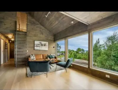 a living room with a table and chairs and windows at Cabin at the end of Skardsøya towards the sea - boat in Bukta