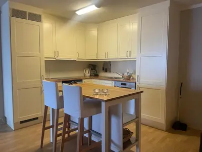 a kitchen with a wooden table and white cabinets at Toppleilighet Midt I Beitostølen in Beitostøl