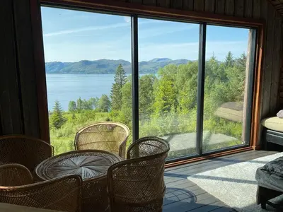 a screened in porch with chairs and a view of a lake at Forest Hideaway With Scenic View in Fiskå