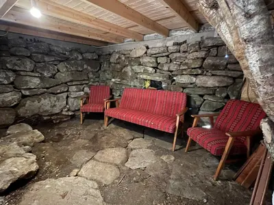 two red chairs and a table in a stone room at Forest Hideaway With Scenic View in Fiskå
