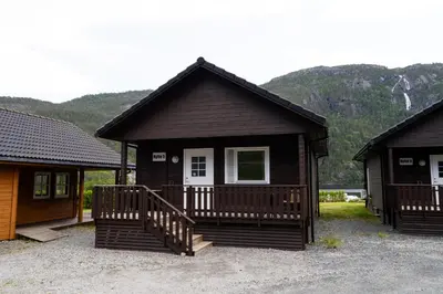 a small cabin with a porch and a white door at Standard Hytte in Fjæra