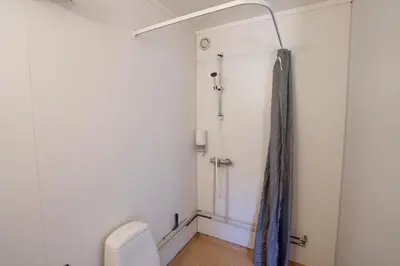 a bathroom with a toilet and a shower curtain at Standard Hytte in Fjæra