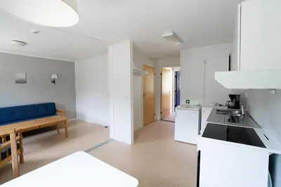 a kitchen with white cabinets and a blue couch at Standard Rom in Fjæra