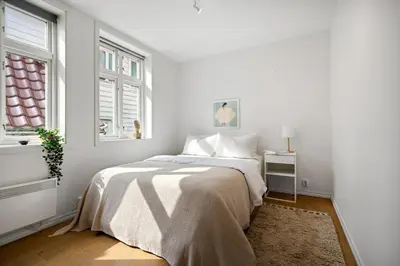 a white bedroom with a bed and a window at Modern apartment near bryggen - classic architecture in Bergen